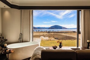 Una habitación con un ventanal que ofrece vistas a un lago y montañas.