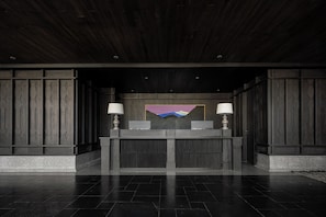 Un mostrador de recepción con dos lámparas, un cuadro y un interior de madera oscura.