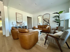A modern living room with leather armchairs, a coffee table, and a large mirror. - 2.8 Miles from Augusta National, this home is the perfect base for the Masters! (Augusta)