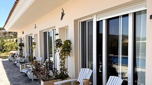 Exterior d'un hotel amb una filera de gandules, plantes en testos i un camí empedrat.