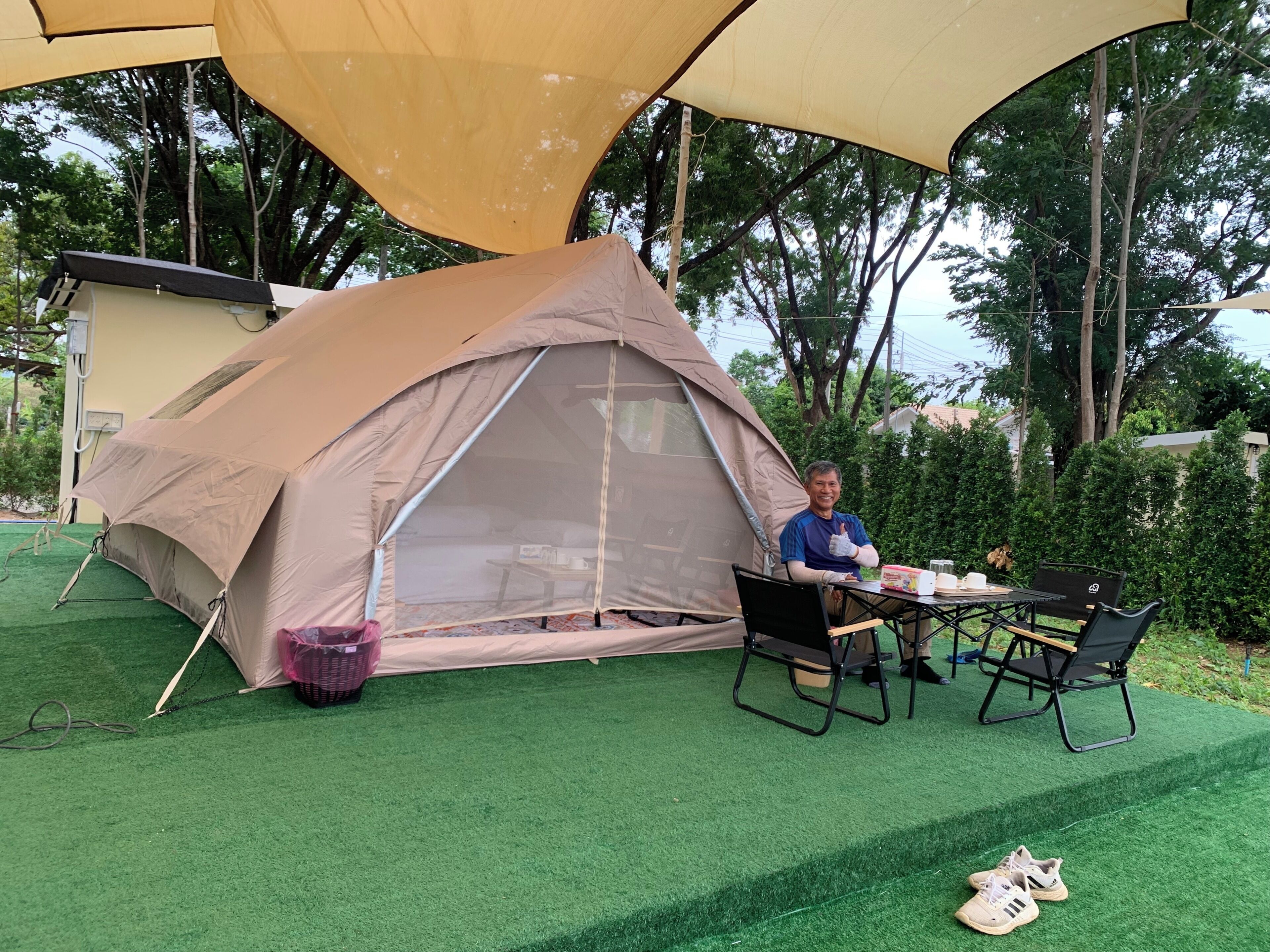 Une tente installée sur une pelouse artificielle, avec une table et des chaises à proximité.