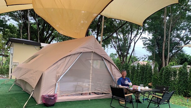 Una carpa montada sobre césped artificial, con una mesa y sillas cerca.