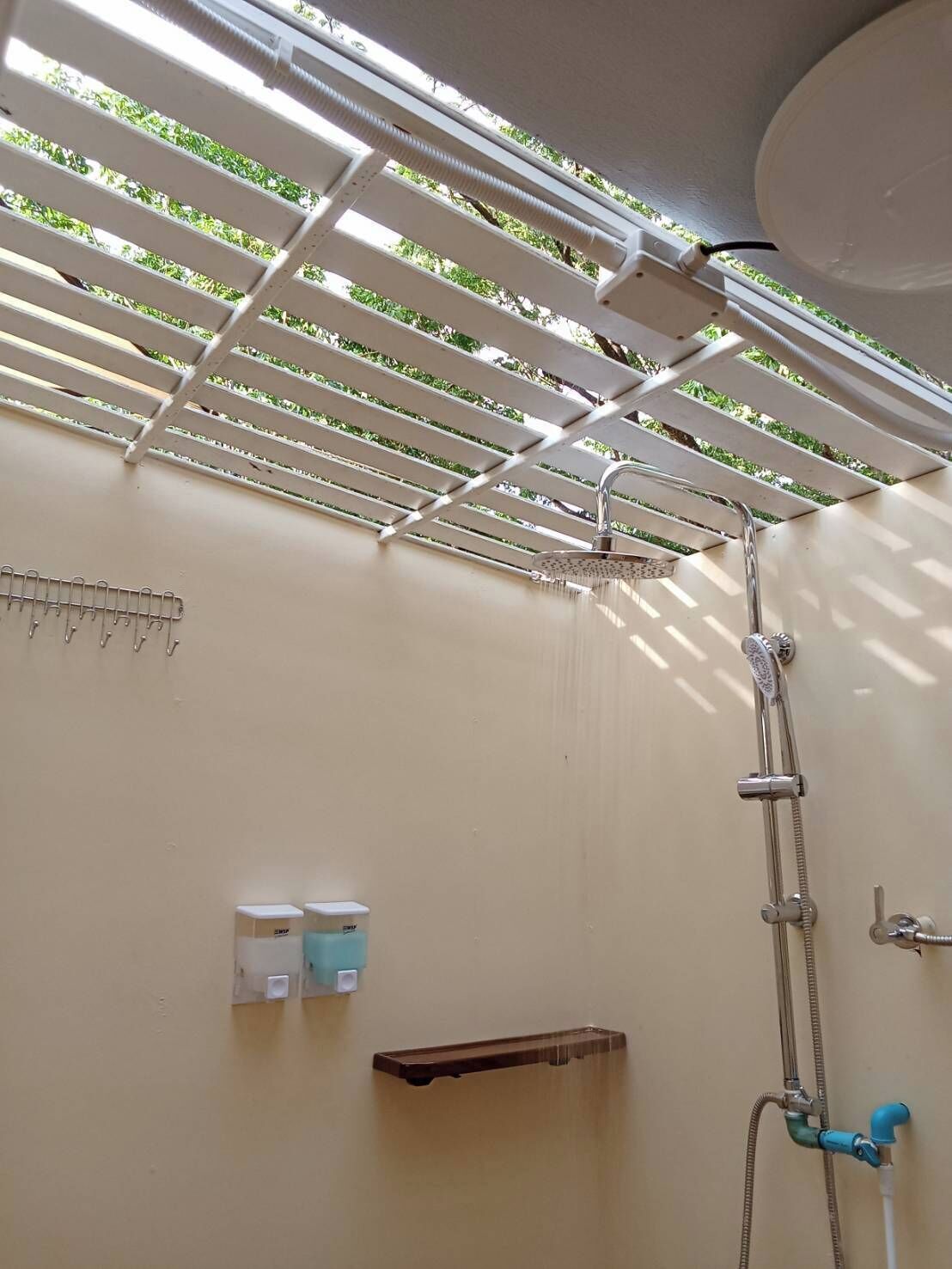 Un espace douche équipé d’un ventilateur de plafond, d’un porte-serviettes et d’une étagère pour les articles de toilette.