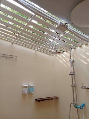 Un espace douche équipé d’un ventilateur de plafond, d’un porte-serviettes et d’une étagère pour les articles de toilette.