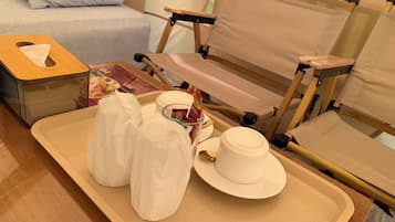 A neatly arranged tray with a tissue box, a cup, and a small container, likely for toiletries, on a wooden table in a hotel room.