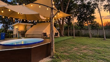 Un patio trasero con piscina, una carpa y luces colgantes.
