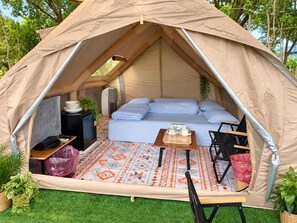 Una carpa con una cama, una mesa con una bandeja y un calentador portátil.