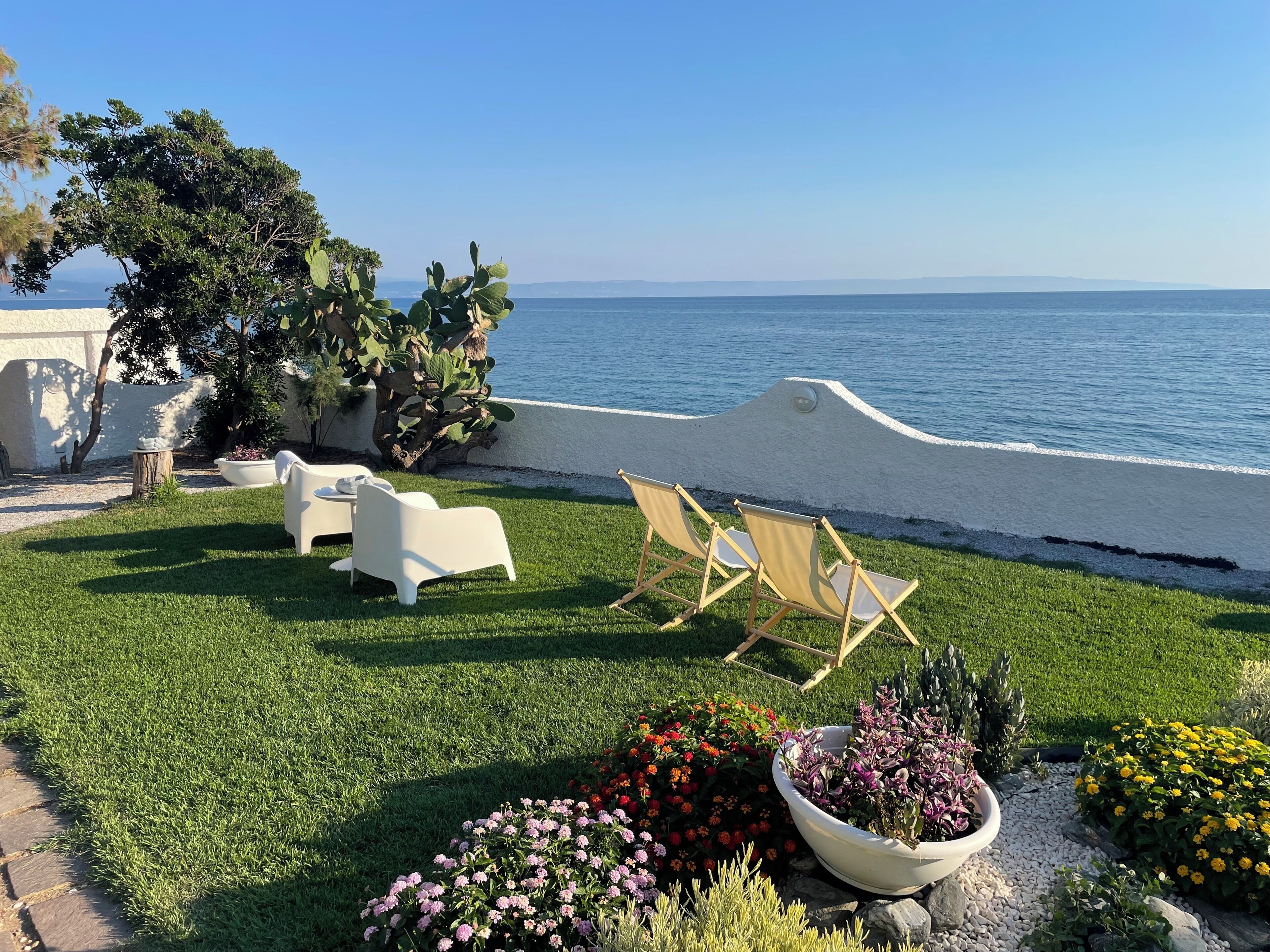 A patio with outdoor seating, a cactus plant, and a view of the sea.