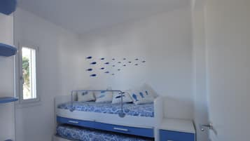 Un dormitorio con una cama individual doble, una ventana, un adorno de peces en la pared y una alfombra estampada.