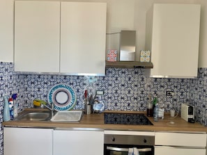 A kitchen with a sink, stove, and cabinets.