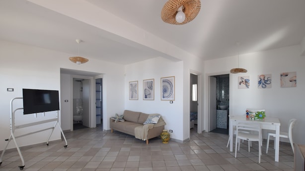 A spacious living area with a sofa, TV, and dining table.