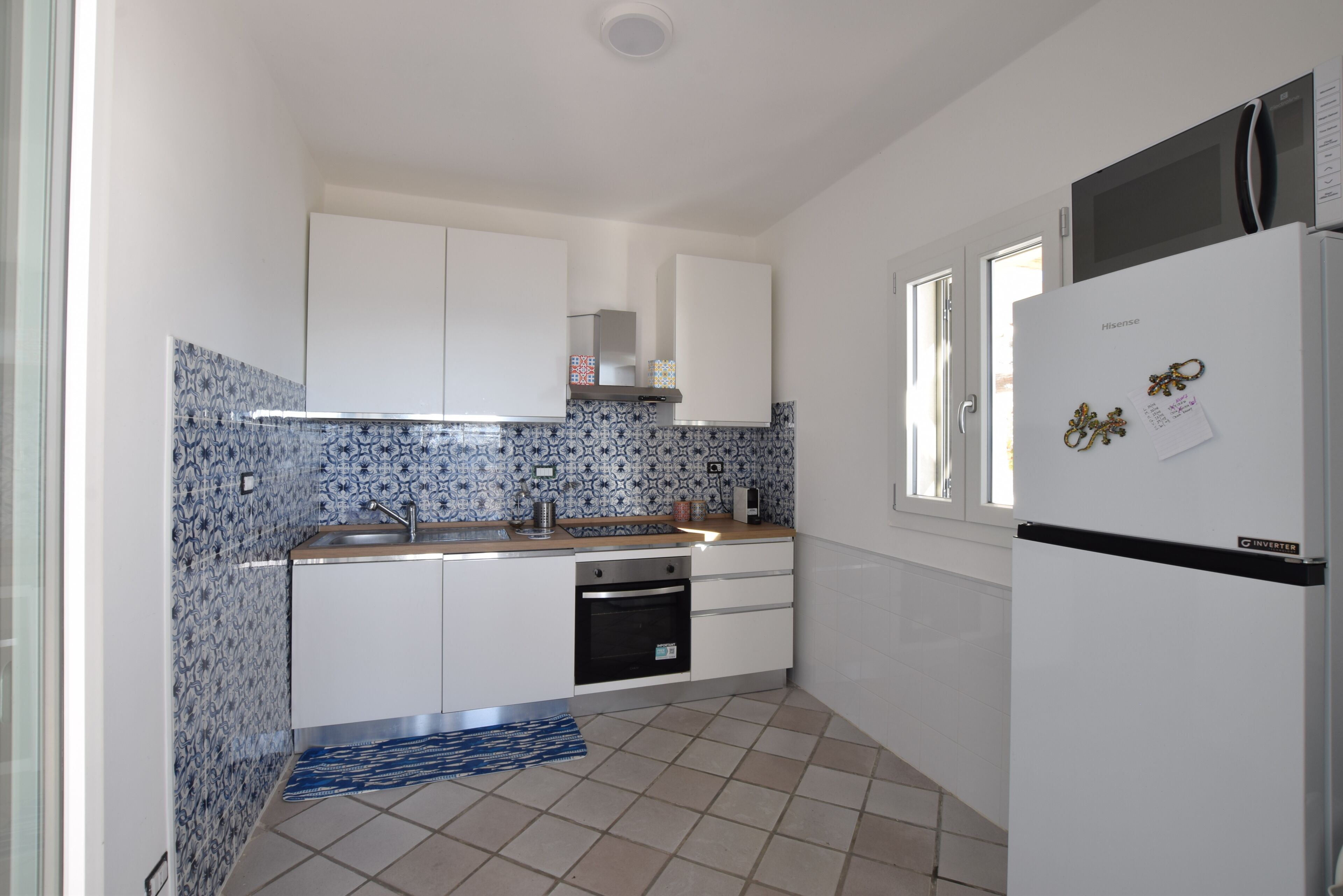 A kitchen with white cabinets, a microwave, a refrigerator, and a patterned backsplash.