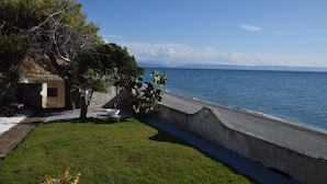 A coastal property with a paved walkway, a small building, and a view of the sea.