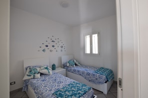 Une chambre avec deux lits, un plafond blanc, une décoration murale représentant des créatures marines et une fenêtre.
