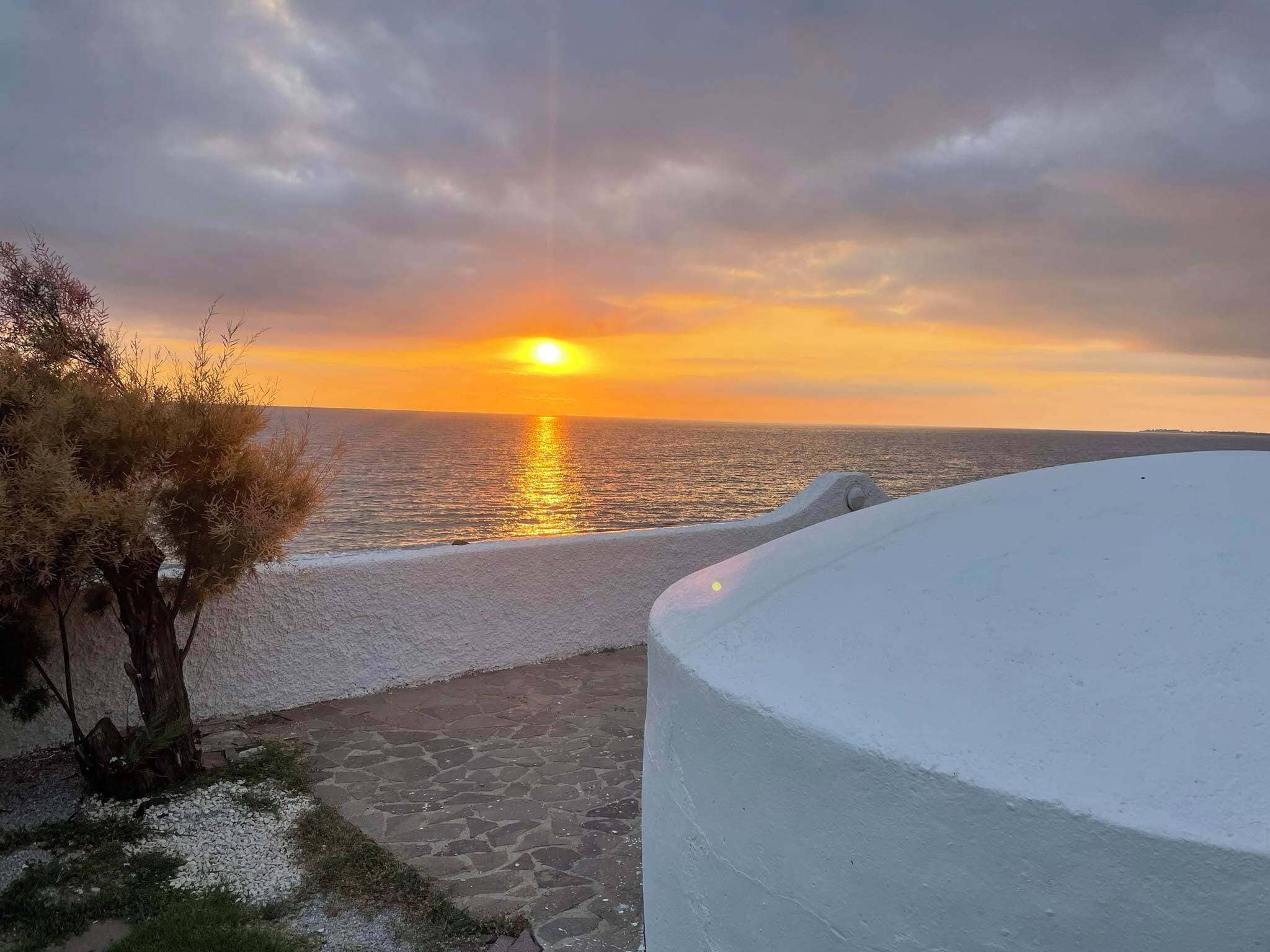 Una vista al atardecer sobre una playa con un camino que lleva a un edificio blanco.