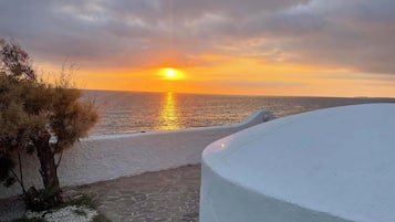 Una vista al atardecer sobre una playa con un camino que lleva a un edificio blanco.