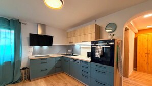 Une cuisine moderne avec des meubles gris, un four noir et un micro-ondes encastré.
