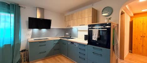 Eine moderne Küche mit grauen Schränken, einem schwarzen Backofen und einer eingebauten Mikrowelle.