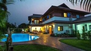 A two-story house with a swimming pool, outdoor seating, and a well-lit patio area. - Oriental Thai Luxury Villa With Private Pool, Chiangmai, Thailand (Tambon San Phi Suea)