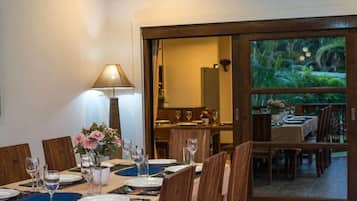 A dining area with a table set for four, a lamp, and a view through a glass door to an outdoor dining space.