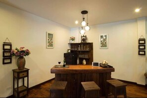 Zona de bar con mostrador de madera, taburetes, una botella de vino y objetos decorativos.