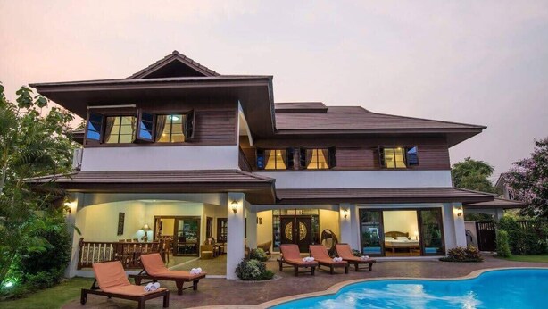 A two-story house with a swimming pool, outdoor seating, and a well-lit interior. - Oriental Thai Luxury Villa With Private Pool, Chiangmai, Thailand (Tambon San Phi Suea)