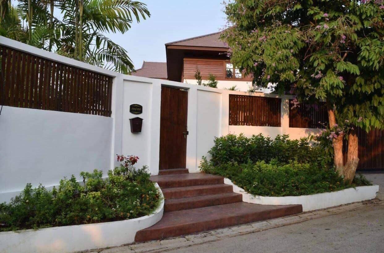 Una propiedad residencial con fachada blanca, puerta de madera y escaleras que conducen a la entrada.