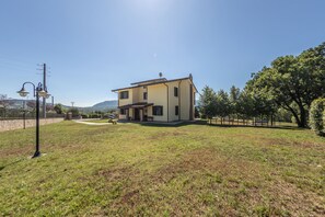 Une maison à deux étages avec un toit plat, un porche à l’avant et un petit jardin.
