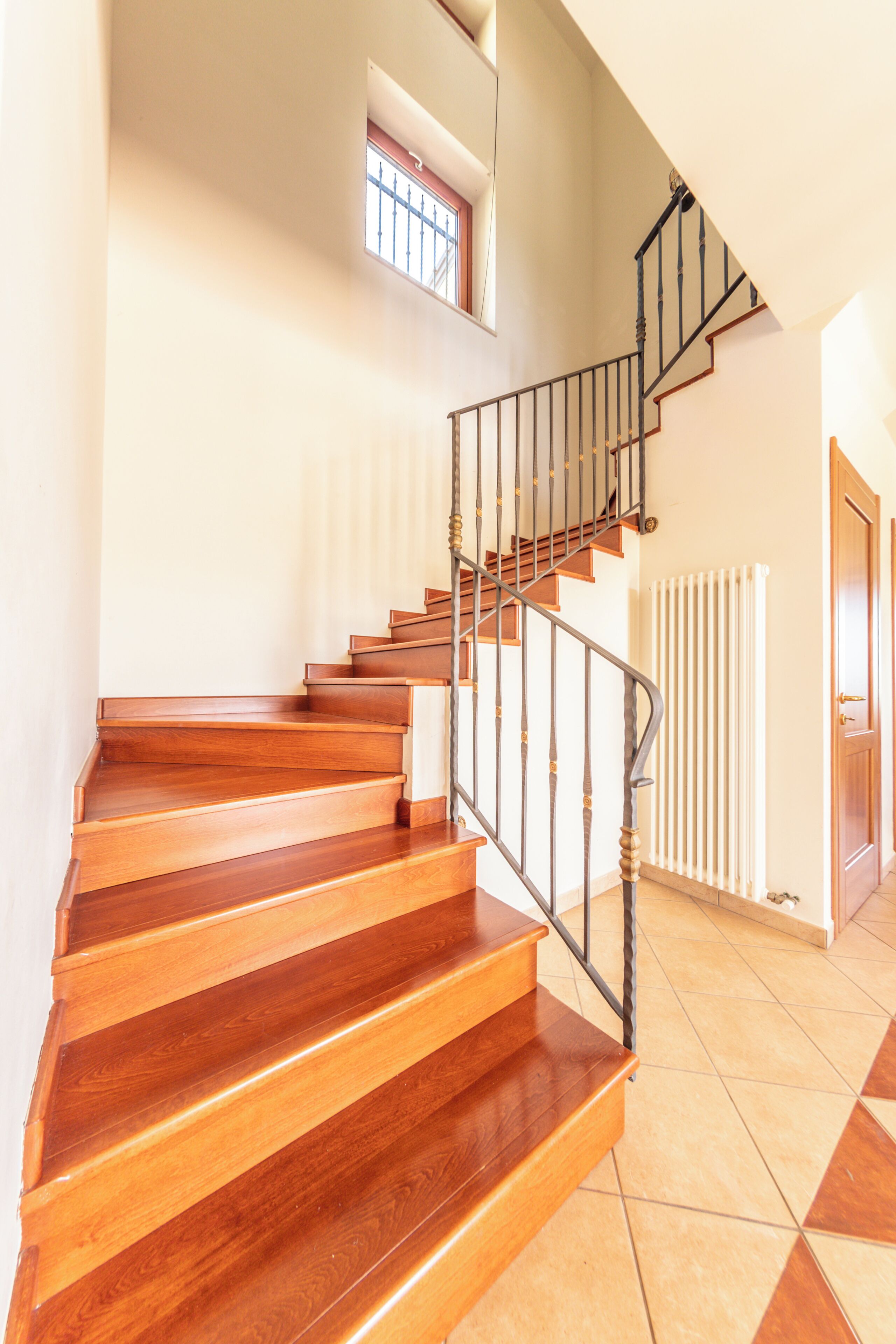 A wooden staircase with a metal railing leading to a landing.