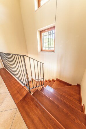 A wooden staircase with a metal railing leading to a landing.
