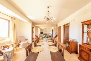 A spacious dining area with a long wooden table, woven placemats, and a chandelier. - Villa Pamela (Cassano Irpino)