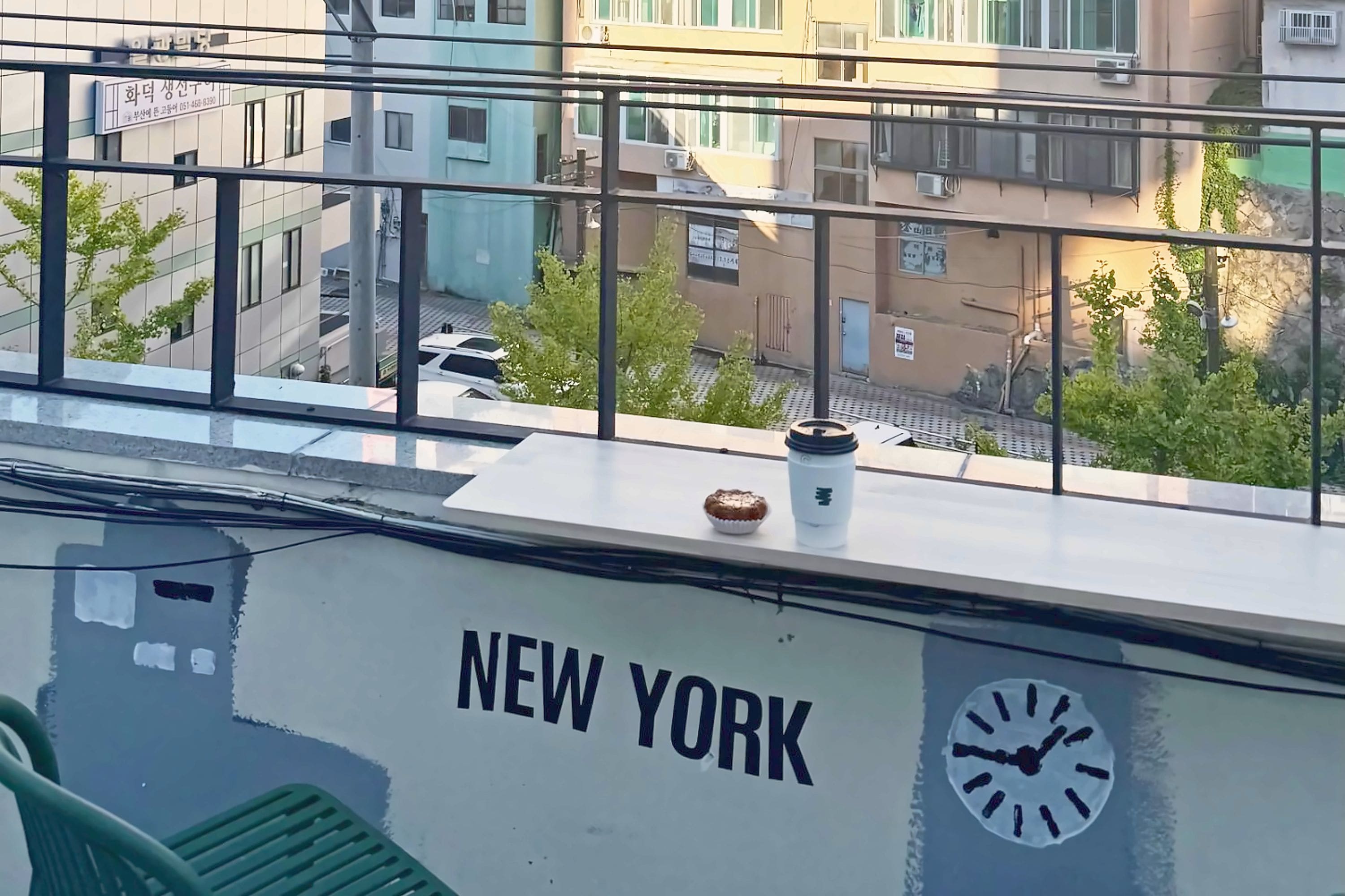 Un edificio con la inscripción 'NEW YORK' en la fachada, un reloj y una ventana con vistas a otros edificios.