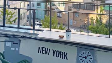 Un edificio con la inscripción 'NEW YORK' en la fachada, un reloj y una ventana con vistas a otros edificios.