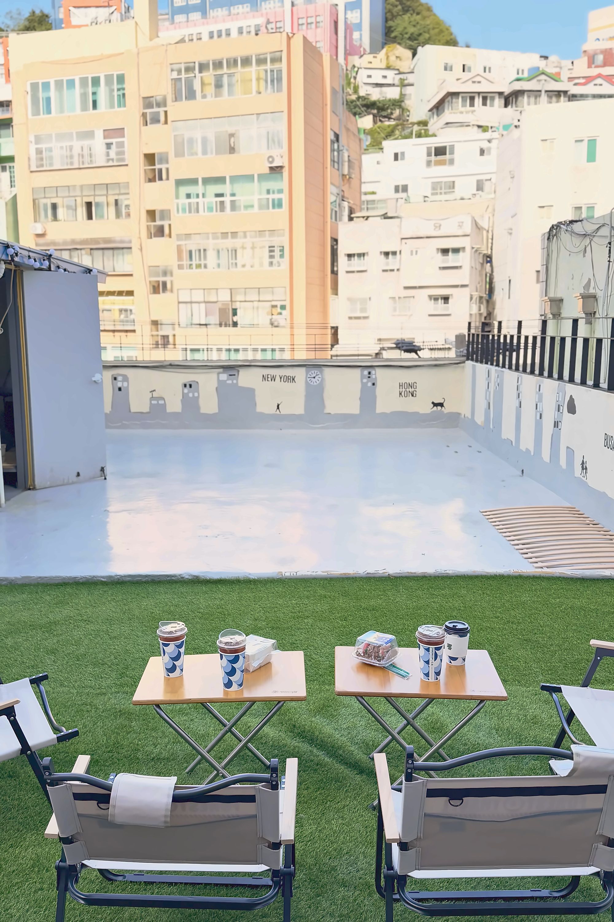 A rooftop terrace with two tables, chairs, and a view of the cityscape.