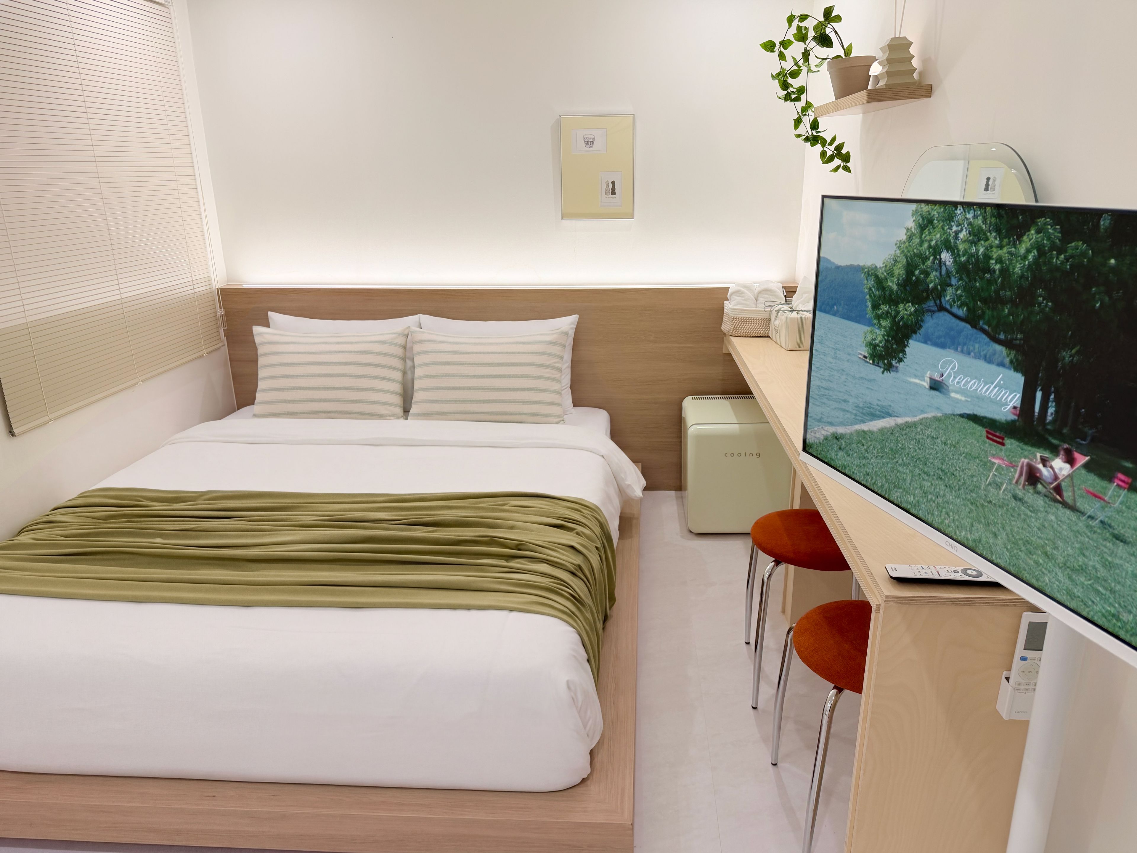 A hotel room with a bed, a desk with a computer, a TV, and a small table with chairs.