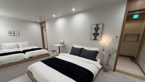 A modern hotel room with two beds, a small table, a wall-mounted light, and a potted plant. - Stay Zam Hotel (Jung-gu)