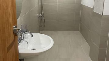 A modern bathroom with a sink, shower, and toilet.