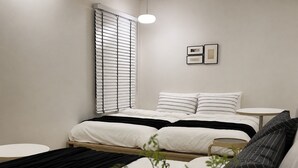 A modern bedroom with a bed, bedside tables, a round table, and a window with blinds. - Stay Zam Hotel (Jung-gu)