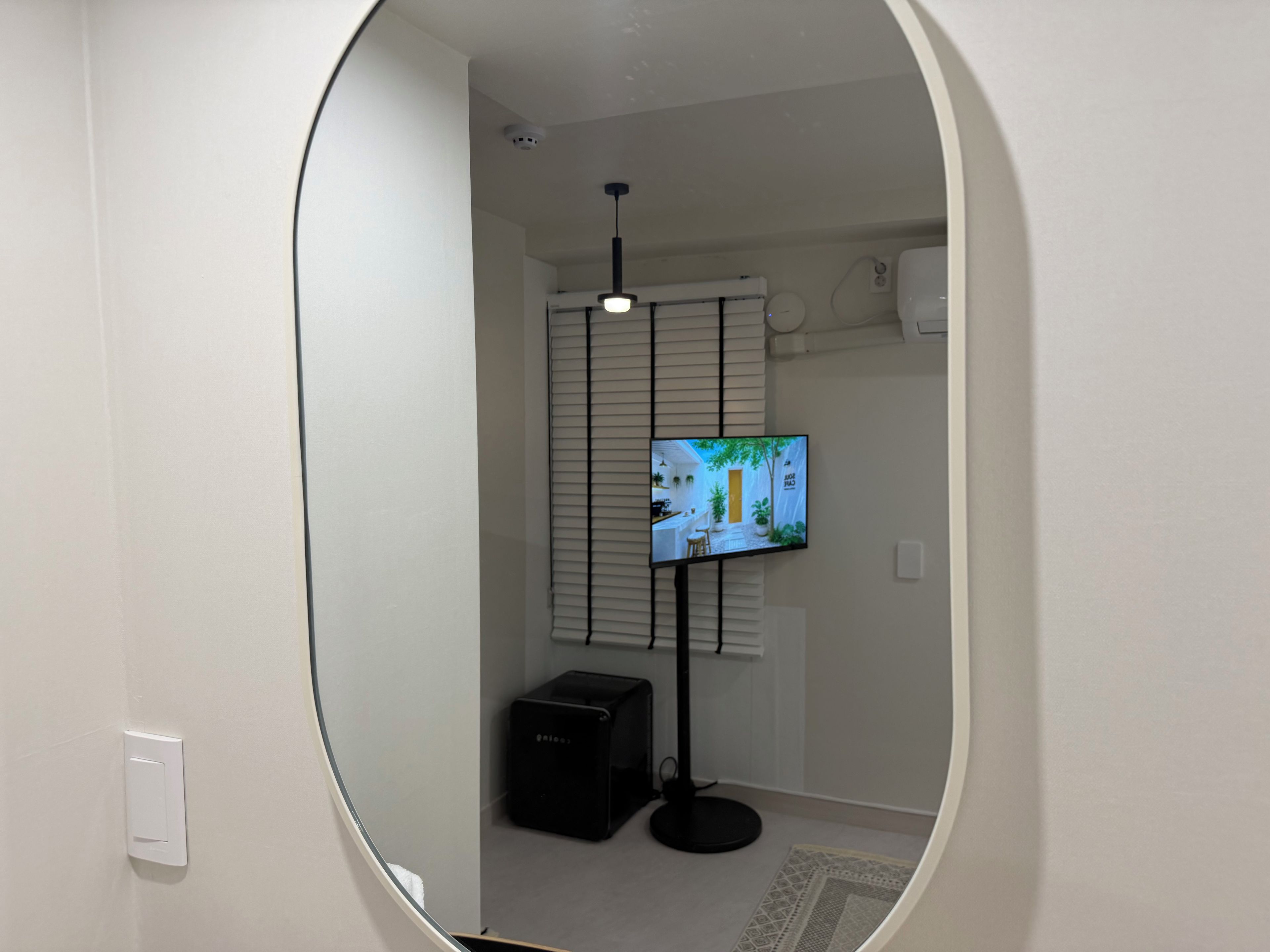 A room with a television on a stand, a ceiling light, and a door.