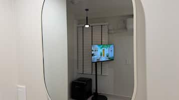 A room with a television on a stand, a ceiling light, and a door.