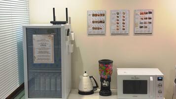 A kitchenette with a refrigerator, microwave, and coffee maker.