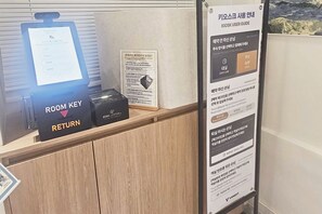 A reception desk with a room key return station and a kiosk user guide.