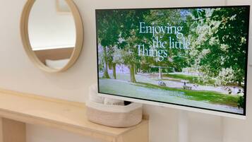Un televisor montado en la pared mostrando una escena de naturaleza con el texto 'Enjoying the little things'.