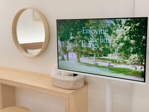 A television mounted on a wall displaying a nature scene with the text 'Enjoying the little things.' - STAY zzZARM Hotel (Busan)