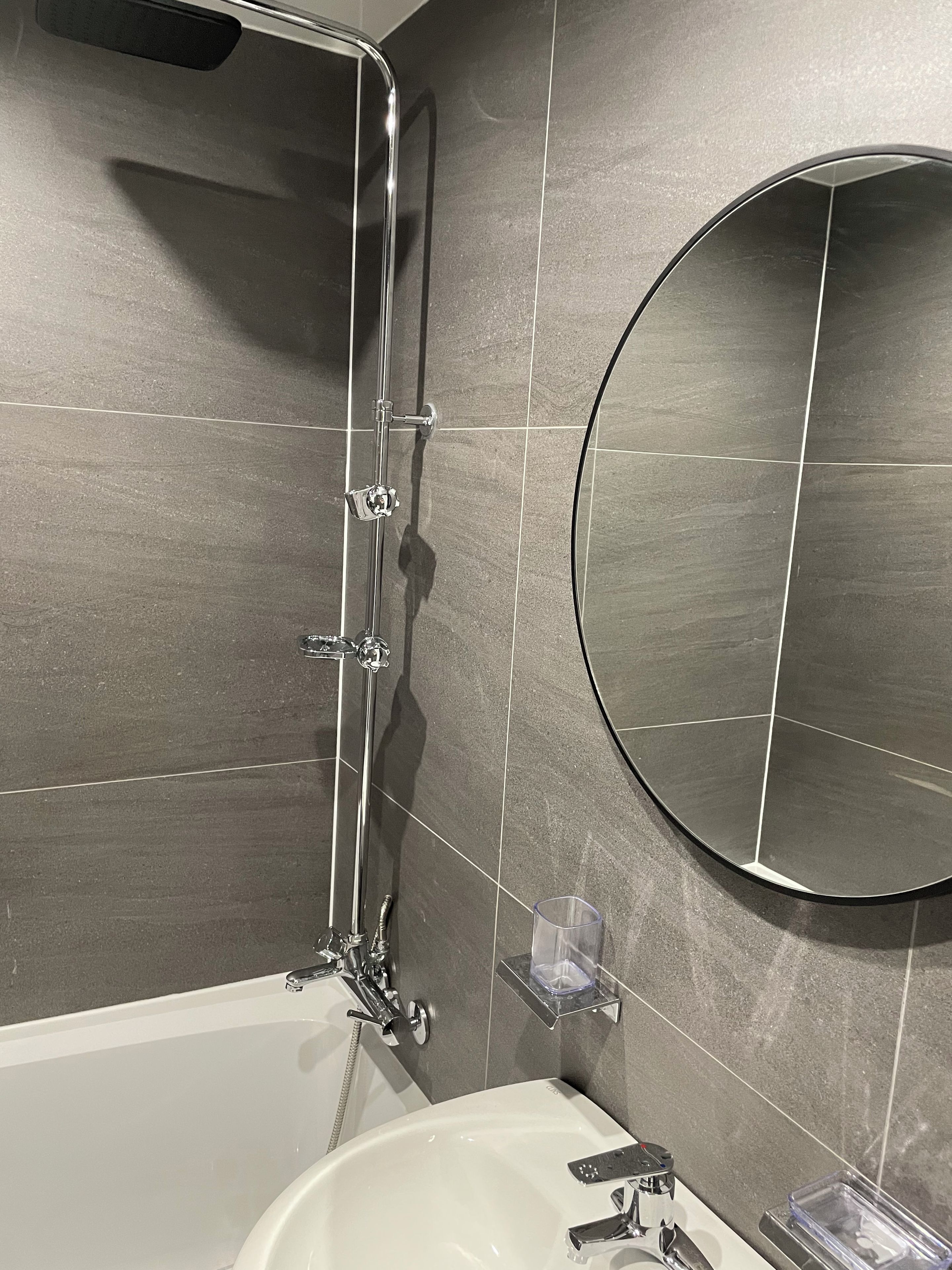 Une salle de bain moderne avec une baignoire, un miroir rond et une douche.