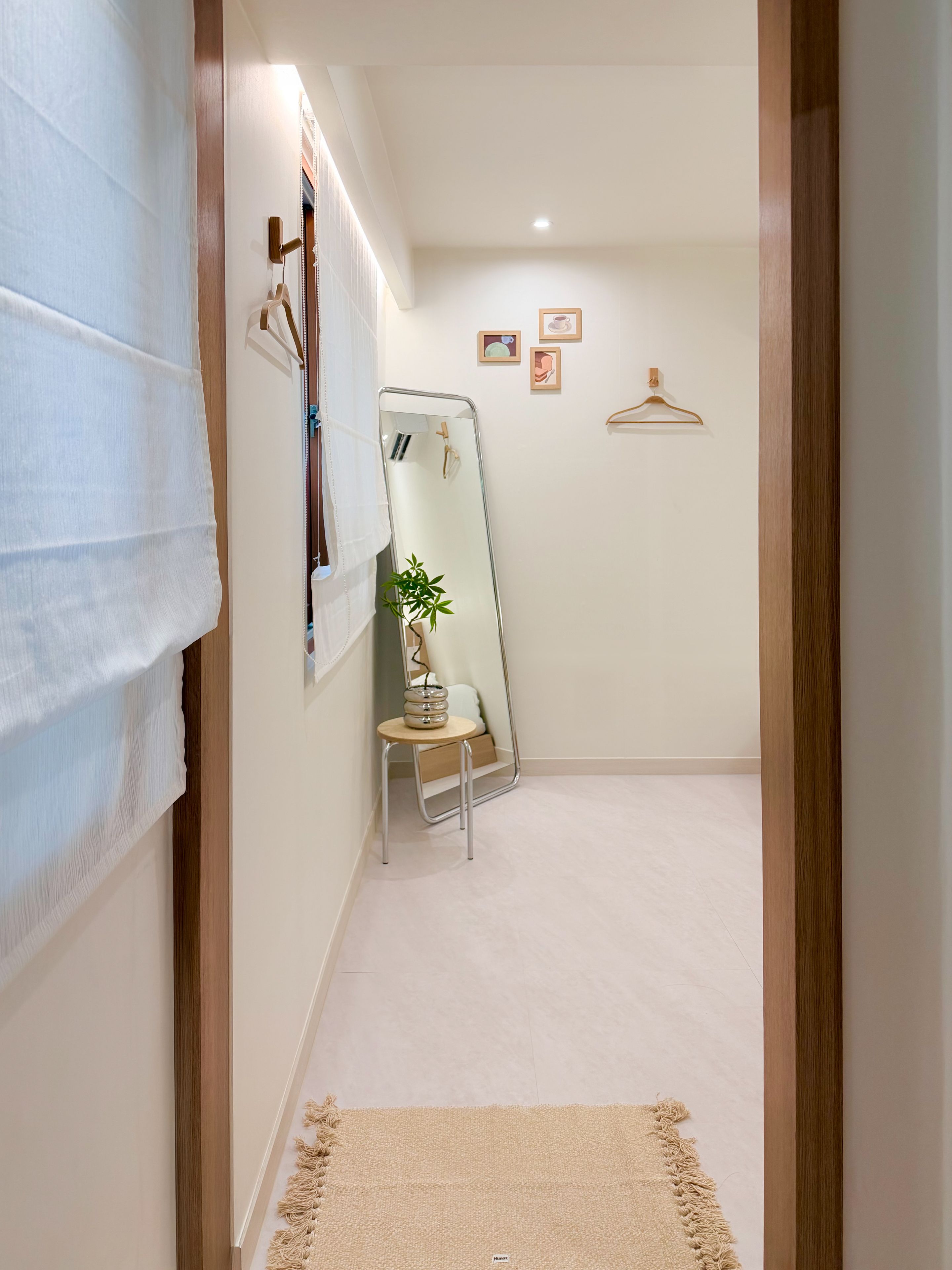 A hallway with a mirror, a small table with a plant, and a hanging garment rack.