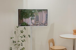 A television mounted on a wall displaying an outdoor scene with a tree and a building.