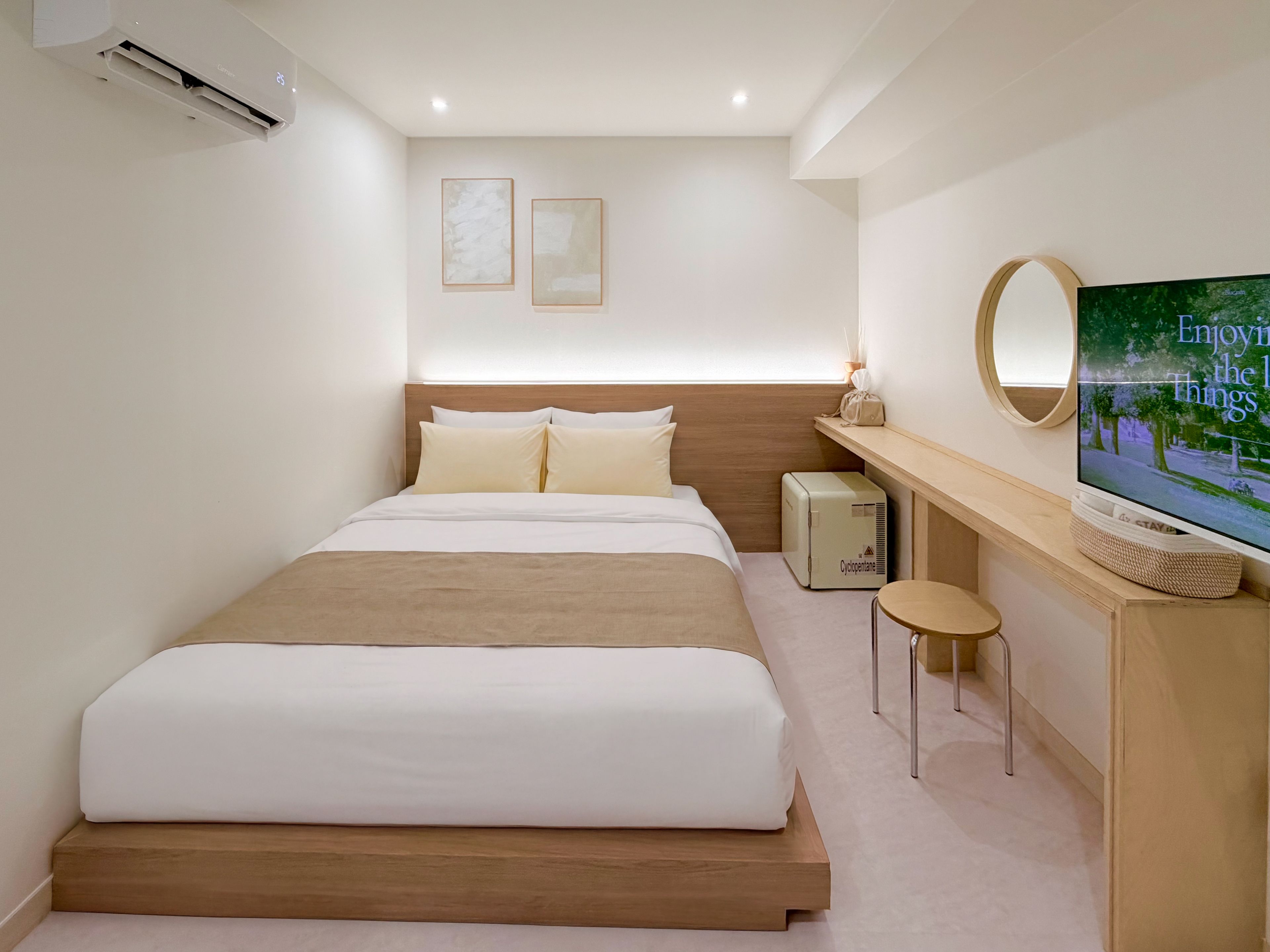 A hotel room with a bed, a television, a small table, and a wall-mounted mirror.