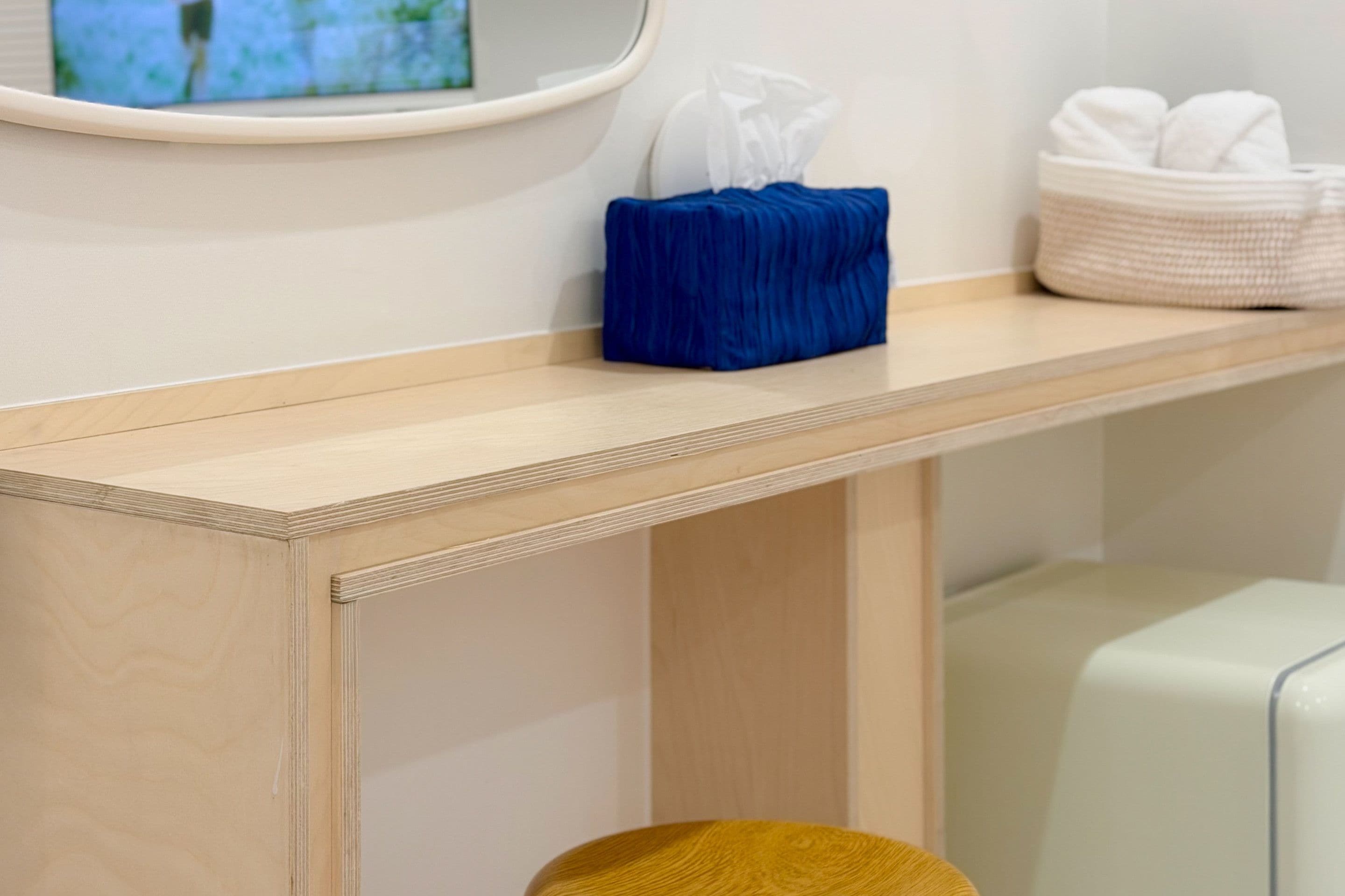 Una consola de madera con un dispensador de pañuelos y una cesta de toallas.
