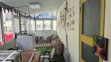 A room with a table, chairs, a small heater, a window with a view, and a door with a mesh screen.